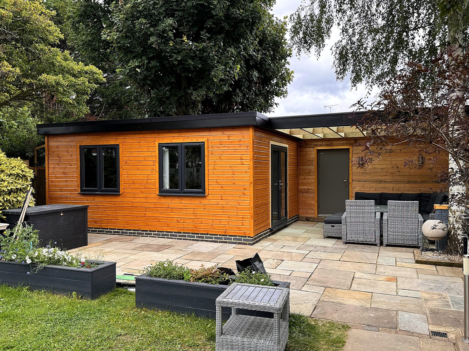 Timber-clad garden room with patio seating area and planters