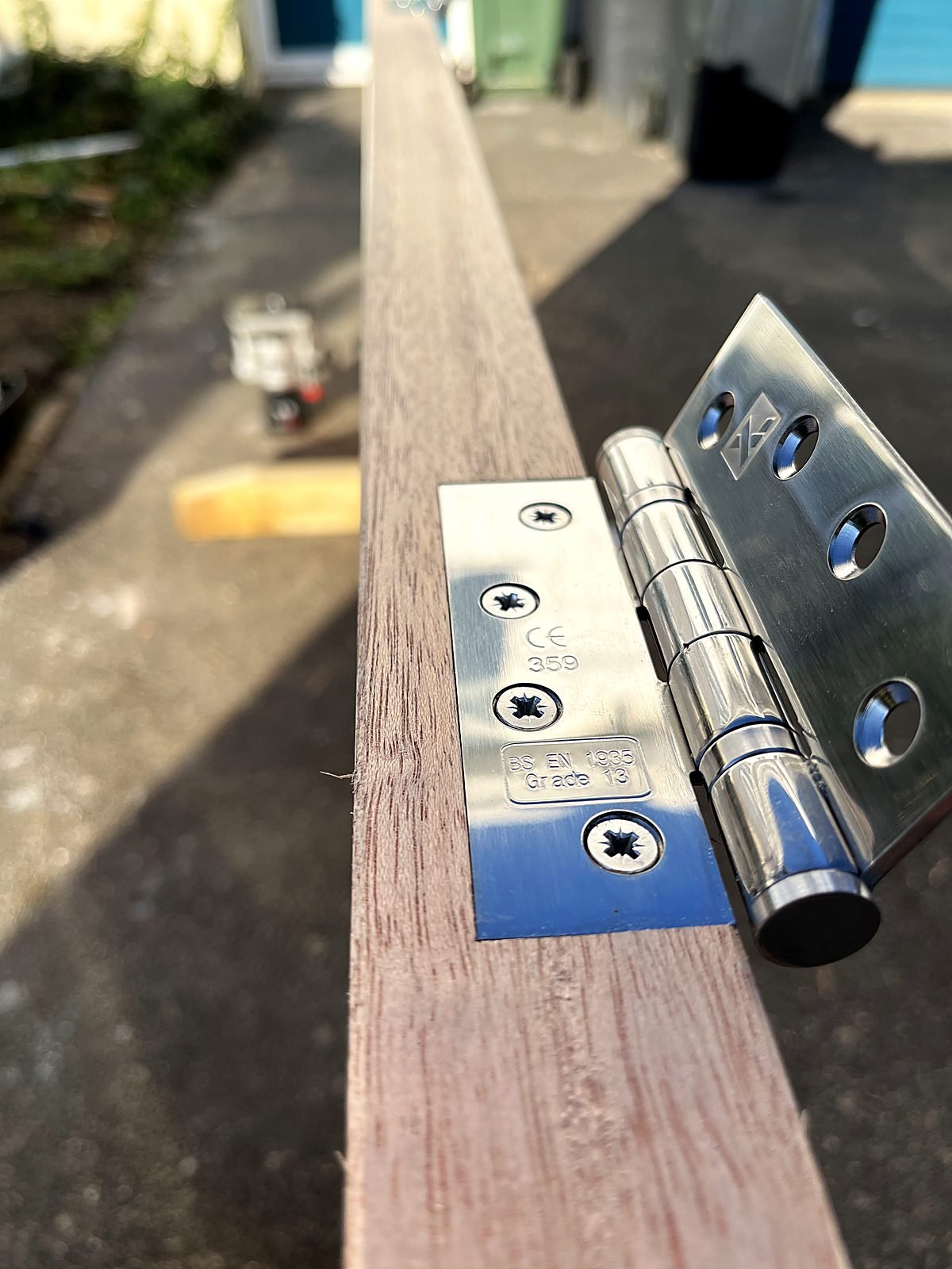 Close-up of a stainless steel ball-bearing hinge fitted flush into a hardwood door edge